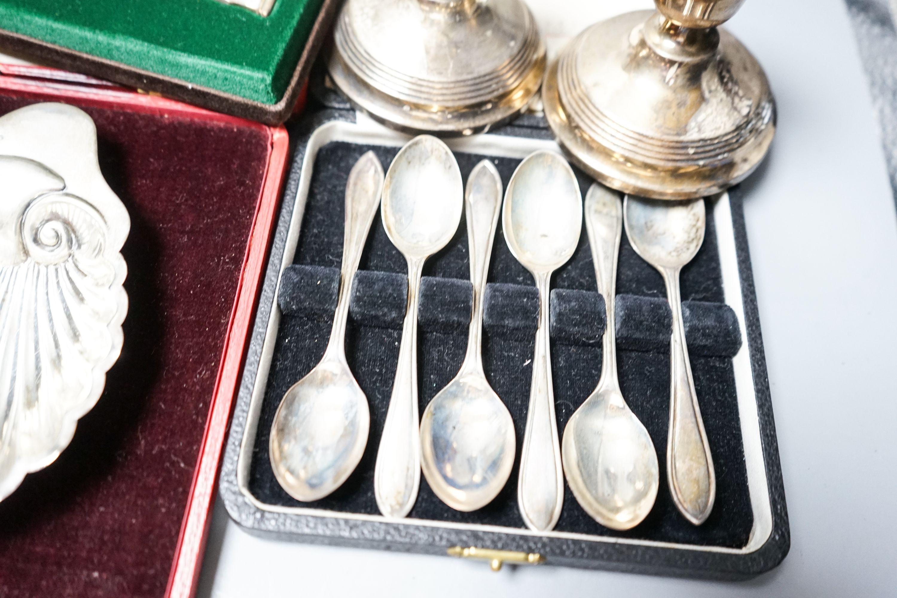 A cased pair of four 1920's silver napkin rings, four other cased items including butter shell and a pair of silver mounted dwarf candlesticks.